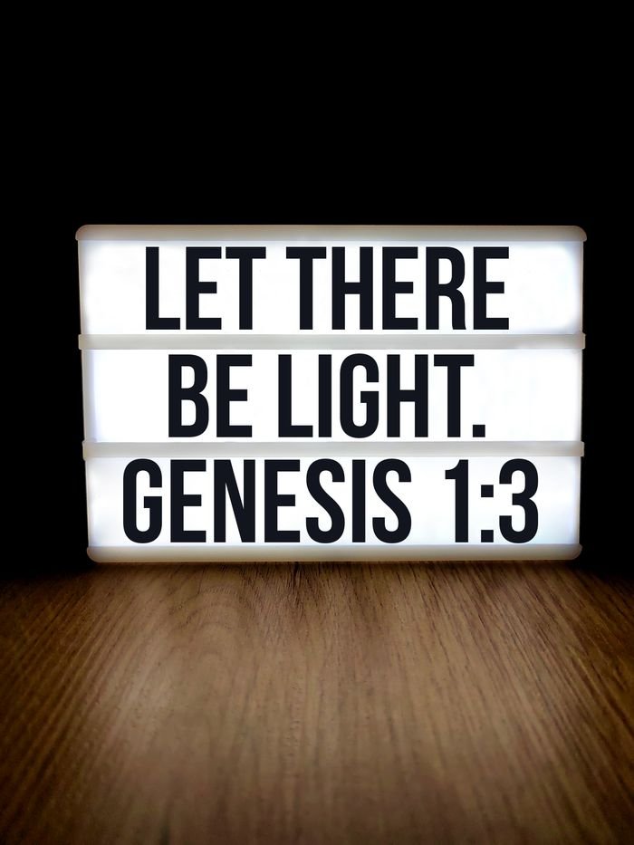 hero-homepage Lightbox displaying Genesis 1:3 'Let There Be Light' on a wooden surface.